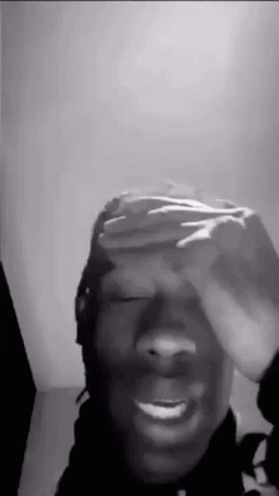 A Black And White Photo Of A Man Covering His Eyes With His Hand . GIF