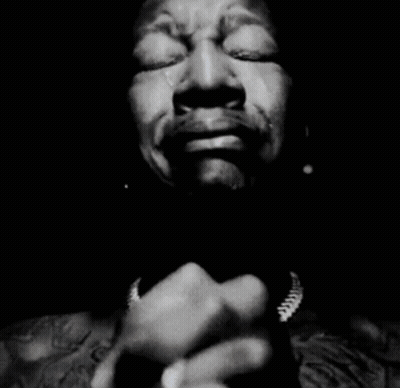 A Black And White Photo Of A Man Covering His Mouth With His Hands GIF