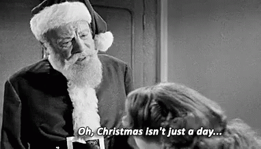 A Black And White Photo Of A Man Dressed As Santa Claus Talking To A Woman . GIF