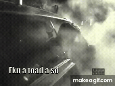 A Black And White Photo Of A Man Driving A Car With Smoke Coming Out Of It . GIF