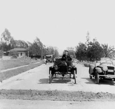 A Black And White Photo Of A Man Driving An Old Car GIF