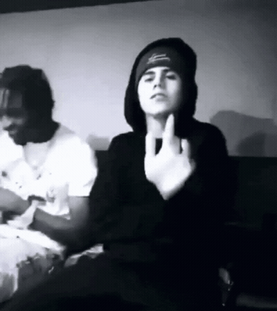A Black And White Photo Of A Man Giving The Middle Finger While Sitting Next To Another Man . GIF