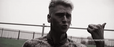 A Black And White Photo Of A Man Giving The Thumbs Up Sign While Standing In Front Of A Fence . GIF