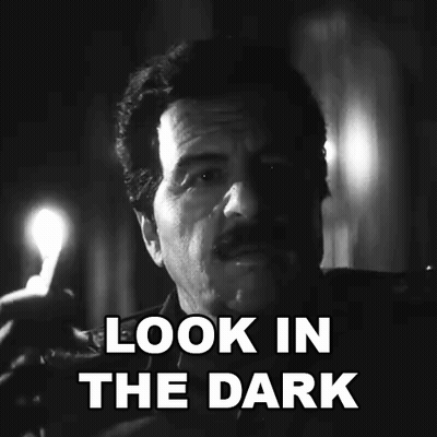 A Black And White Photo Of A Man Holding A Candle With The Words `` Look In The Dark '' . GIF