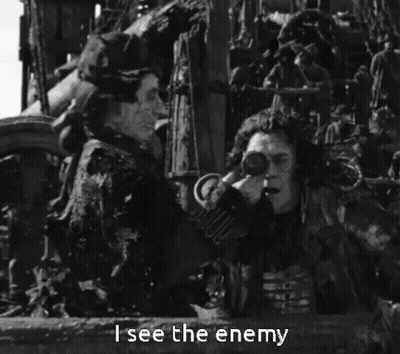 A Black And White Photo Of A Man Holding Binoculars With The Words " I See The Enemy " Below Him GIF