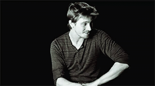 A Black And White Photo Of A Man In A Black Shirt Making A Funny Face . GIF
