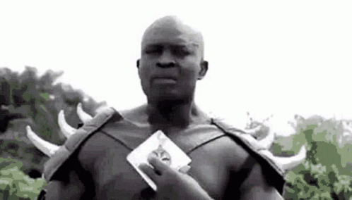 A Black And White Photo Of A Man In A Costume Holding A Card In His Hand . GIF
