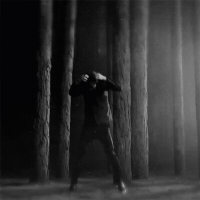 A Black And White Photo Of A Man In A Forest GIF