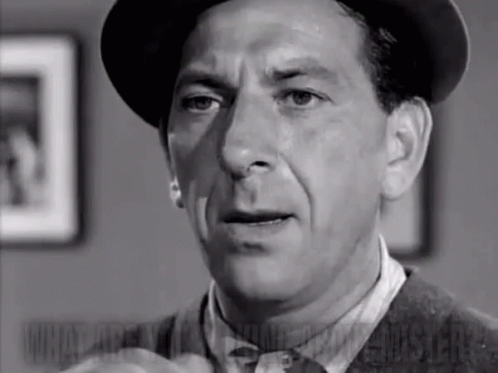A Black And White Photo Of A Man In A Hat And Tie . GIF