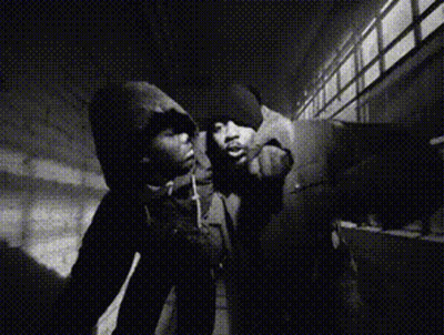 A Black And White Photo Of A Man In A Hoodie Smoking A Cigarette GIF