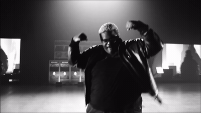 A Black And White Photo Of A Man In A Jacket Dancing GIF