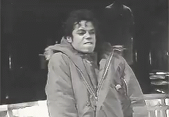 A Black And White Photo Of A Man In A Jacket Standing Next To A Railing . GIF