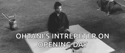 A Black And White Photo Of A Man In A Kimono Sitting On A White Surface . GIF