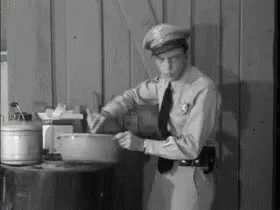 A Black And White Photo Of A Man In A Police Uniform Holding A Bowl . GIF