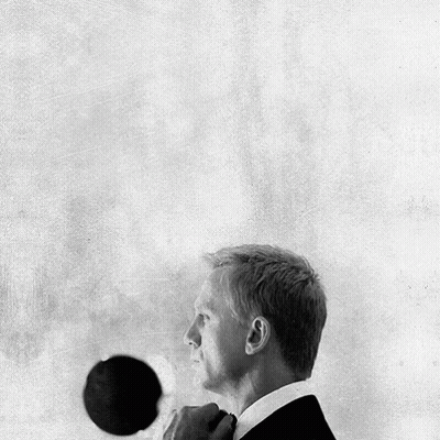 A Black And White Photo Of A Man In A Suit Adjusting His Tie GIF