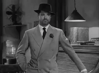 A Black And White Photo Of A Man In A Suit And Hat GIF