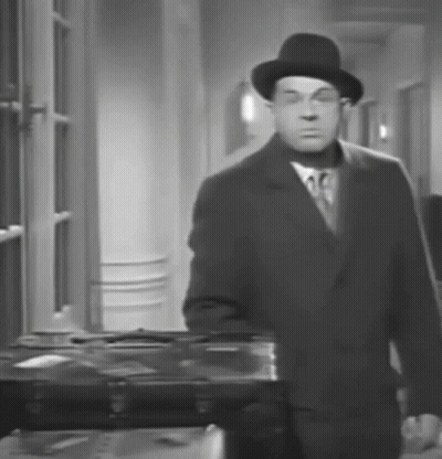 A Black And White Photo Of A Man In A Suit And Hat GIF