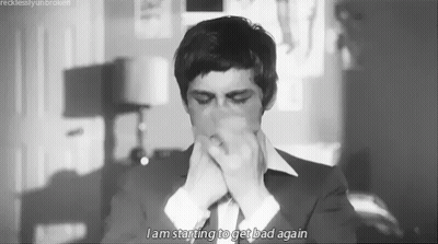 A Black And White Photo Of A Man In A Suit And Tie Covering His Mouth . GIF