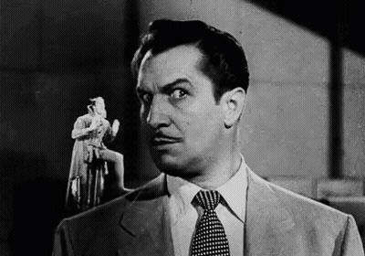 A Black And White Photo Of A Man In A Suit And Tie Holding A Statue . GIF