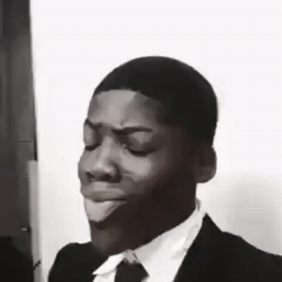 A Black And White Photo Of A Man In A Suit And Tie Making A Face . GIF