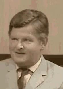A Black And White Photo Of A Man In A Suit And Tie Making A Surprised Face . GIF