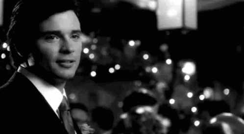 A Black And White Photo Of A Man In A Suit And Tie Standing In Front Of A Crowd . GIF