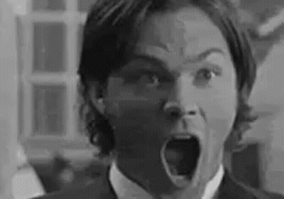 A Black And White Photo Of A Man In A Suit And Tie With His Mouth Open . GIF