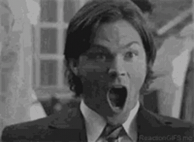 A Black And White Photo Of A Man In A Suit And Tie With His Mouth Wide Open . GIF