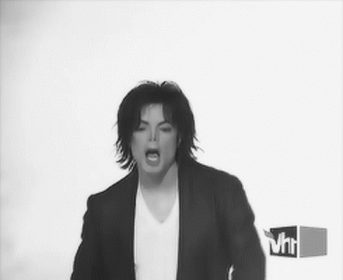 A Black And White Photo Of A Man In A Suit And White Shirt GIF