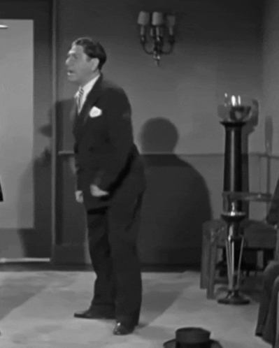 A Black And White Photo Of A Man In A Suit Dancing GIF