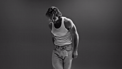 A Black And White Photo Of A Man In A Tank Top And Jeans GIF