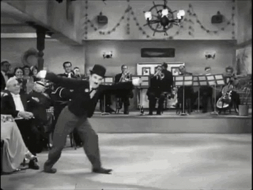 A Black And White Photo Of A Man In A Top Hat Dancing On A Stage . GIF