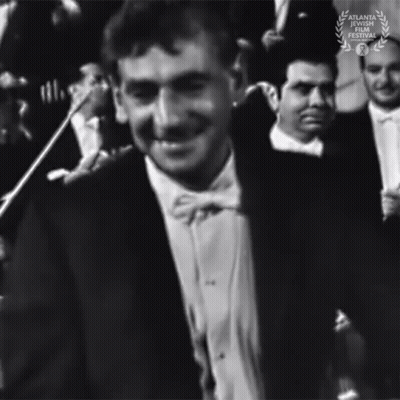 A Black And White Photo Of A Man In A Tuxedo And Bow Tie With A Laurel Wreath In The Corner GIF
