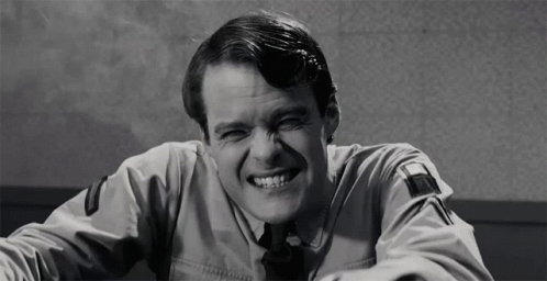 A Black And White Photo Of A Man In A Uniform Laughing GIF