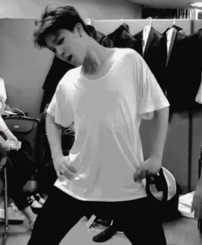 A Black And White Photo Of A Man In A White T-Shirt Dancing In A Room . GIF