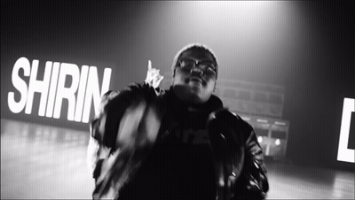 A Black And White Photo Of A Man In Front Of A Sign That Says ' Shrin ' GIF