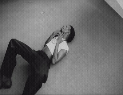 A Black And White Photo Of A Man Laying On The Floor With His Hands On His Face GIF