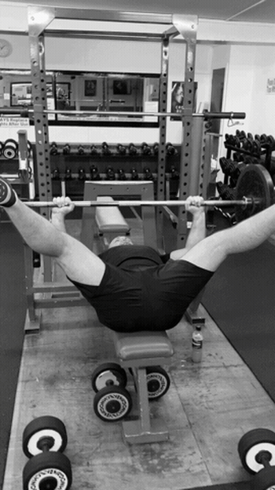 A Black And White Photo Of A Man Lifting Weights GIF