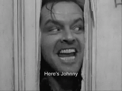A Black And White Photo Of A Man Looking Through A Door With The Words `` Here 'S Johnny '' Written Below Him . GIF