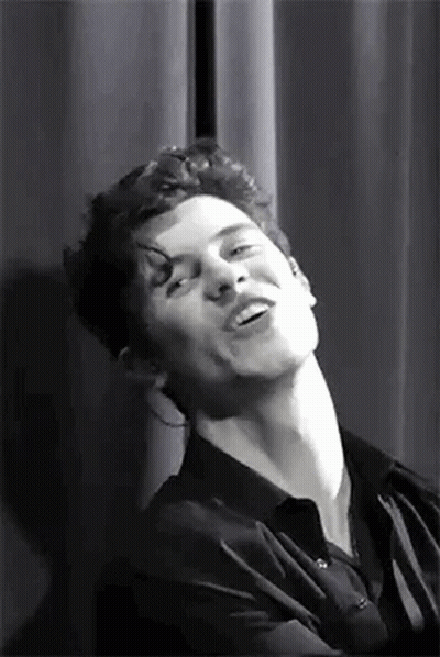 A Black And White Photo Of A Man Making A Funny Face While Standing In Front Of A Curtain . GIF