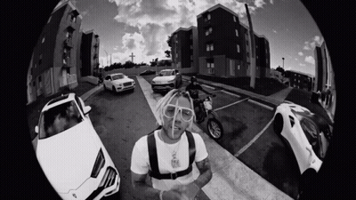 A Black And White Photo Of A Man On A Motorcycle Surrounded By Cars GIF