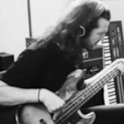 A Black And White Photo Of A Man Playing A Bass Guitar In A Recording Studio . GIF
