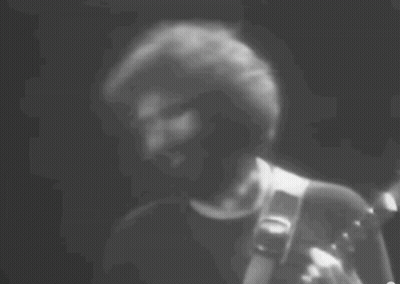 A Black And White Photo Of A Man Playing A Guitar . GIF