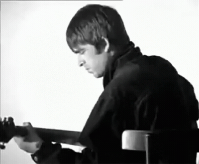 A Black And White Photo Of A Man Playing A Guitar . GIF