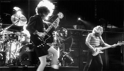 A Black And White Photo Of A Man Playing A Guitar On Stage . GIF