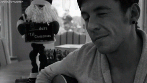 A Black And White Photo Of A Man Playing A Guitar With A Sign That Says Days Till Christmas GIF