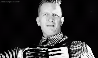 A Black And White Photo Of A Man Playing An Accordion GIF