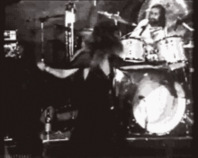A Black And White Photo Of A Man Playing Drums In A Band GIF