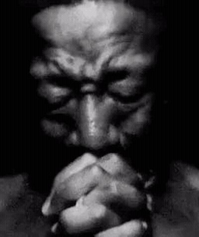 A Black And White Photo Of A Man Praying With His Eyes Closed . GIF