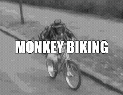 A Black And White Photo Of A Man Riding A Bicycle With The Words Monkey Biking Written Above Him GIF